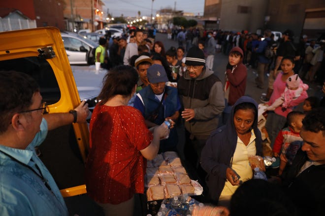 Well-wishers distribute food to migrants outside a sports complex where more than 5,000 Central Americans were sheltering, in Tijuana, Mexico, on Wednesday. [AP PHOTO/REBECCA BLACKWELL]