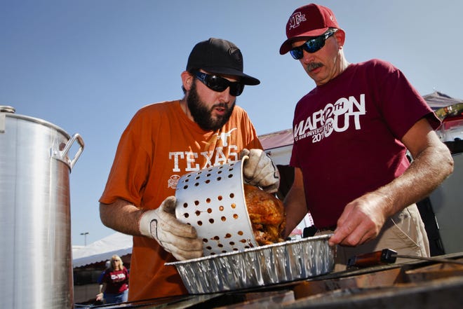 Longhorns fan Ben Hovland, left, and his Aggies fan dad Bruce Hovland, right, fry a turkey during their Thanksgiving Day tailgate before the start of the Texas A&M Aggies vs University of Texas Longhorns rivalry NCAA football game at Kyle Field on Thursday, November 24, 2011 in College Station, Texas. (Patrick T. Fallon/The Dallas Morning News)
