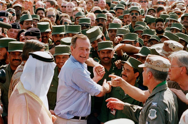 FILE - In this Nov. 22, 1990 file photo, President George H.W. Bush is greeted by Saudi troops and others as he arrives in Dhahran, Saudi Arabia, for a Thanksgiving visit. Bush died at the age of 94 on Friday, Nov. 30, 2018, about eight months after the death of his wife, Barbara Bush. (AP Photo/J. Scott Applewhite, File)