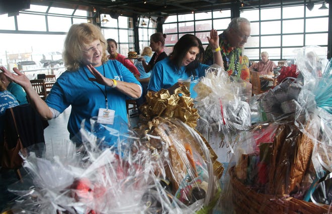 Carla Trant and Cheryl Kerivan, both of Panama City, sing along to Jimmy Buffett as they look at gift baskets for auction during the Hurricane Michael relief party at Margaritaville in Destin. The event was organized by the Emerald Coast Parrot Head Club, with proceeds benefiting Catholic Charities of Northwest Florida. [PHOTOS BY MICHAEL SNYDER/DAILY NEWS]