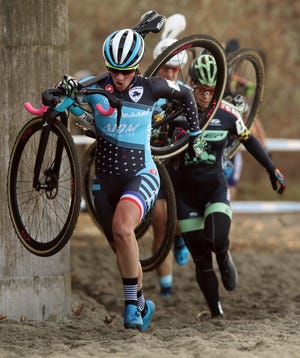 Caroline Mani, of France, carries her bike across a beach area during a race in the Women Elite class on Saturday at the 14th annual NBX Gran Prix of Cylocross at Goddard Park in Warwick. [The Providence Journal / Bob Breidenbach]