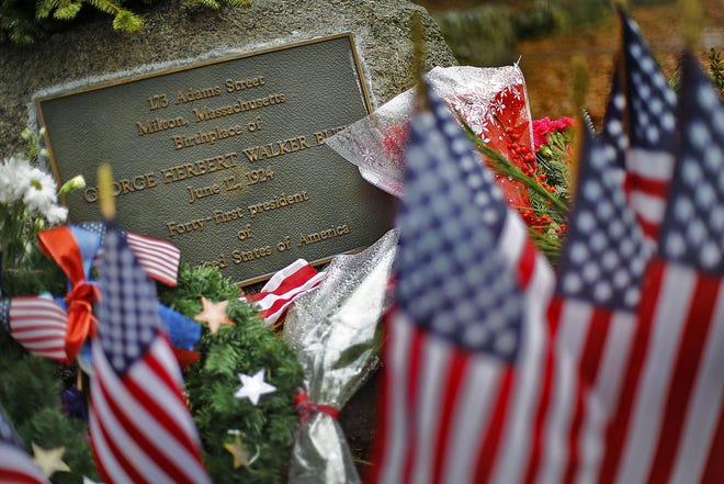 Mourners leave flags and flowers for former President George H.W. Bush at his Milton birthplace on Adams Street on Sunday , Dec. 2 , 2018. (Greg Derr/The Patriot Ledger)