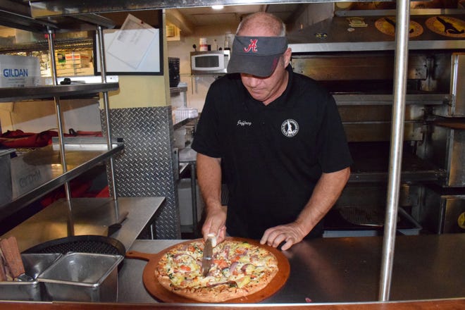 Jeff Goodman, founder and owner of Bruno's Pizza, slices a hot pie. [NATHAN COBB/THE SUN]