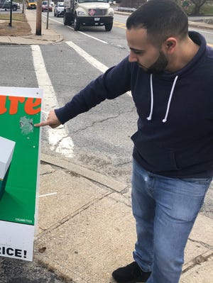 Saleh Khalil points to a sign outside a Johnston store where he said an offensive sticker had been placed. [The Providence Journal / Kevin G. Andrade]