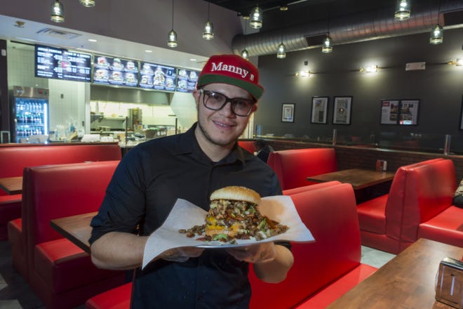 Manny Corona, owner of Manny's Restaurant, with a signature Bombo burger. The popular eatery moved to a location on Bear Valley Road to accommodate demand for their burgers. [James Quigg, Daily Press]