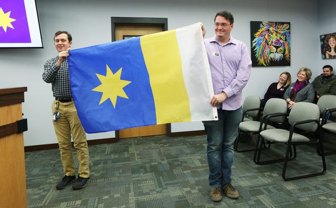 Jackson Swearer, left, holds the flag up with Charles Johnston as they show council members the direction the flag is to be flown when attached to a flag pole during the City Council meeting at City Hall Tuesday, Dec. 4, 2018. [Sandra J. Miburn/HutchNews]