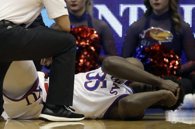 Kansas center Udoka Azubuike is aided by training staff after suffering a right ankle injury during Tuesday night's game against Wofford at Allen Fieldhouse in Lawrence. KU coach Bill Self said Azubuike is "out indefinitely" with a rolled ankle. [Orlin Wagner/The Associated Press]
