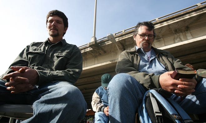 Sam Cole, left, and Mike Featherston, right, bow their heads in prayer during service held at Church Under the Bridge. [American-Statesman 2010]
