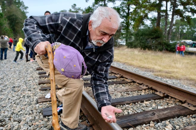Mark Levasseur retrieves coins he placed on the rails Thursday before George H.W. Bush's funeral train passed through Todd Mission. [Ken Herman / American-Statesman]