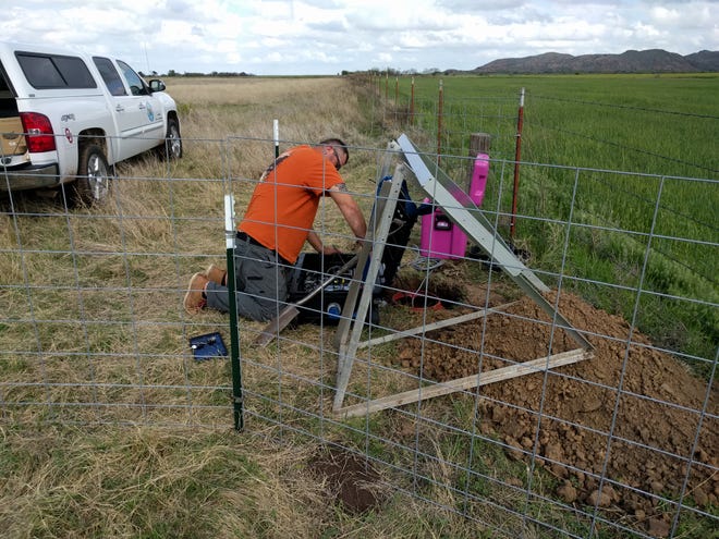 Isaac Woelfel, a field technician at the Oklahoma Geological Survey, installs a seismometer near Quartz Mountain. Each seismic station is powered by a battery that is charged using energy generated by a solar panel and communicates to the survey's network using cellular technology.