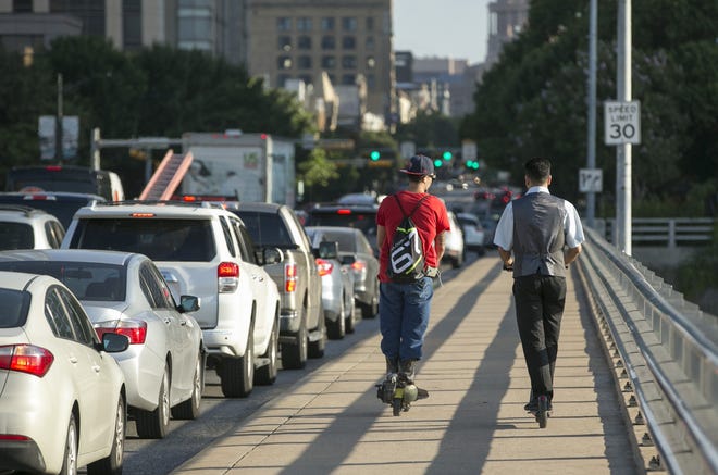 Men ride scooters on the sidewalk on the the Ann Richards Congress Avenue Bridge on Wednesday September 19, 2018. JAY JANNER / AMERICAN-STATESMAN