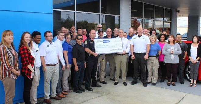 Surrounded by his employees and police officers, Crestview Chevrolet dealership owner Allen Turner (right side of check) presents a check to Deputy Police Chief Jamie Grant and Crestview Citizens Police Academy Alumni President Ed Corbett for the annual Cops For Kids program. [BRIAN HUGHES/CRESTVIEW POLICE DEPARTMENT]