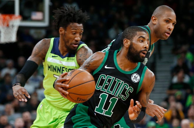 Boston Celtics' Kyrie Irving, center, drives as Minnesota Timberwolves' Robert Covington, left, pursues during the first half of an NBA basketball game Saturday, Dec. 1, 2018, in Minneapolis. At right rear is Celtics' Al Horford. (AP Photo/Jim Mone)