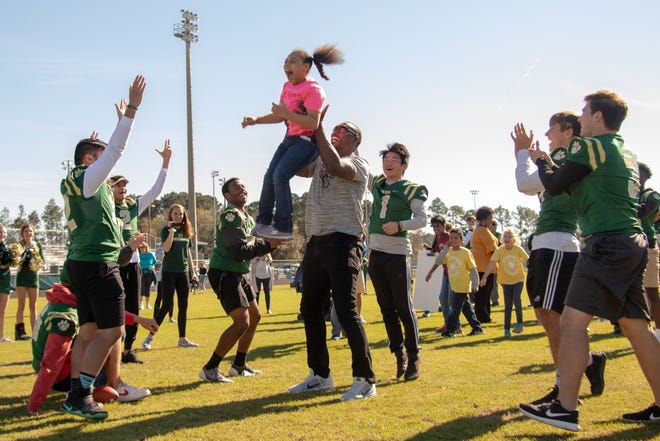 Ayris Pollard is held in the air by her father, Marcus, after scoring a touchdown during Victory Day on Friday at Nease High. The Nease football team joined with students who are differently abled from four St. Johns County elementary schools for a day of fun and learning football. [WILL BROWN/THE RECORD]