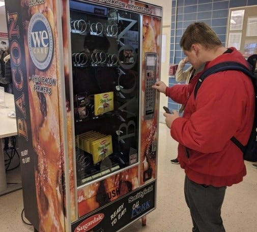 Nick Vales, a sophomore construction management major at Ohio State University, buys a back of Sugardale bacon slices from the school's bacon vending machine. [JD Malone/Columbus Dispatch]