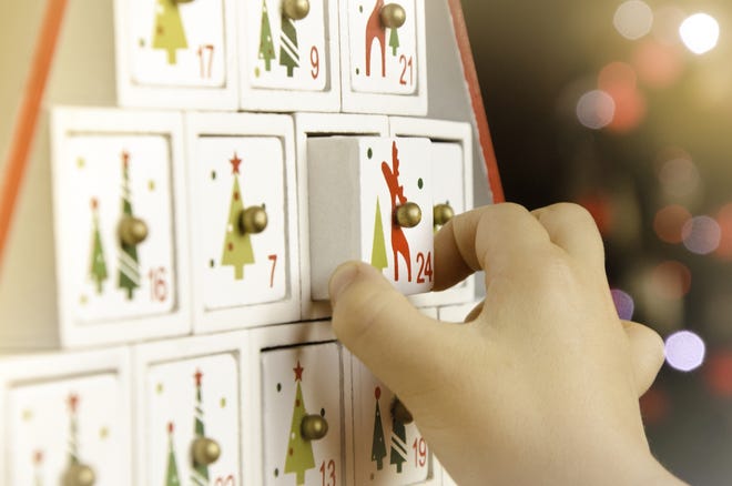 Child's hand pulling the last drawer (number 24) of a wooden advent calendar Christmas tree. (Getty Images)