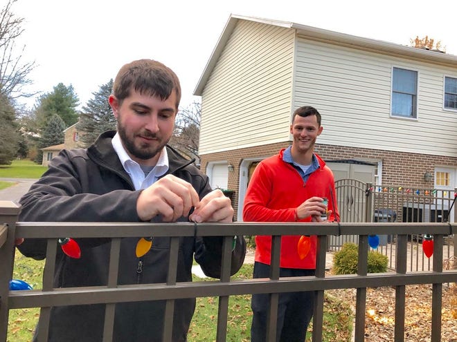 Hooverville teachers Kyle McNew, left, and Casey Hedrick, work on stringing lights around the back fence of Curry’s yard Monday evening. JOHN IRWIN/ THE RECORD HERALD