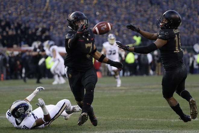 Army's Jaylon McClinton, center, intercepts a pass tipped by teammate Mike Reynolds, right, that was intended for Navy's Mychal Cooper during the first half Saturday. [Matt Slocum/The Associated Press]