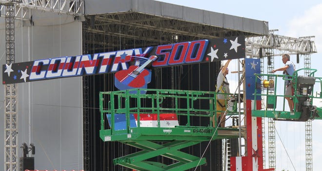 The Country 500 festival logo is put into place on Wednesday on the infield at Daytona International Speedway. The mammoth music festival, now in its third year, will go on rain or shine. Meanwhile, area hoteliers are reporting cancellations because of the forecast for a rainy weekend. [News-Journal/David Tucker]