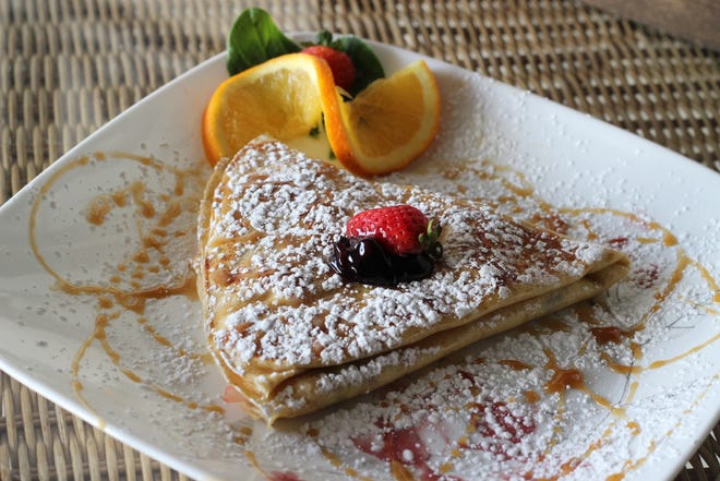 The fruit and cream cheese crepe is a thin layer of batter filled with cream cheese, cherries, strawberries, blueberries and bananas. It is topped with a dollop of fruit puree and a strawberry and sprinkled with powdered sugar. [Savanna Maue/The Capitla-Journal]