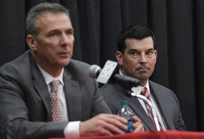 Incoming Ohio State head football coach and current offensive coordinator Ryan Day listens to outgoing head coach Urban Meyer during a press conference to announce Meyer's retirement and Day's hiring as head football coach at Ohio State's Fawcett Center in Columbus on Dec. 4, 2018. [Adam Cairns]