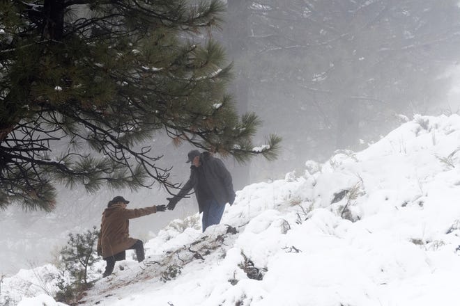 A hiker reaches out for help as visitors turned out to to play in the new coat of snow covering the mountains, Friday Dec. 7, 2018 in Wrightwood, Calif. Meanwhile, governors and local officials from Texas to Virginia have declared emergencies ahead of the arrival of a harsh wintry storm to free up funds and manpower to help mitigate the storm's effect. (James Quigg/The Daily Press via AP)