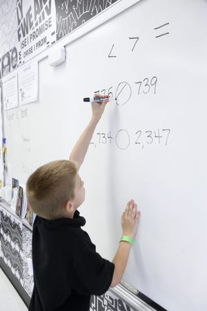Fourth-grader Nate Keyser, 10, marks a less-than symbol between the numbers 725 and 739 at Akron's I Promise School in August. [Karen Schiely/Beacon Journal/Ohio.com file photo]
