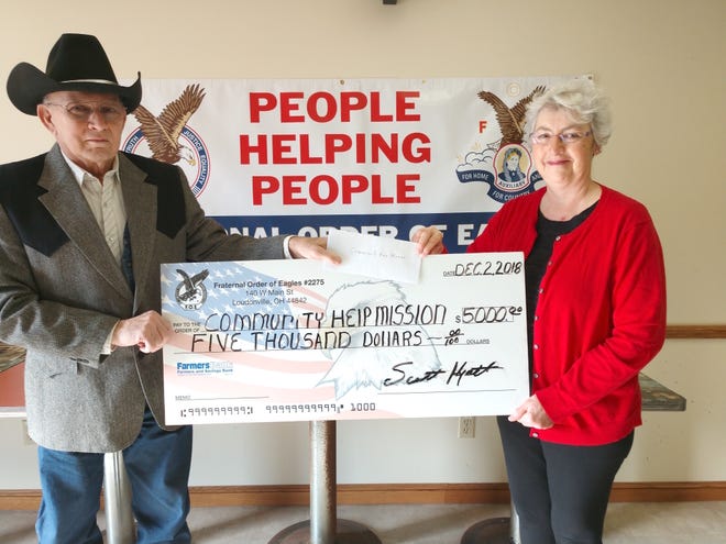 Roger Lowe, trustee of the Fraternal Order of Eagles Aerie 2275, Loudonville, presents a check for $5,000 to Karen Motz, who with Pat Pearl serves as co-manager of the Community Help Mission in Loudonville. Eagles raised the money through its Community Gifts Campaign.