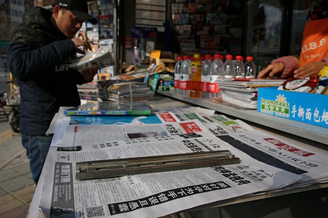 A man arranges magazines near newspapers with the headlines of China outcry against U.S. on the detention of Huawei's chief financial officer, Meng Wanzhou, at a news stand in Beijing, Monday, Dec. 10, 2018. China has summoned the U.S. ambassador to Beijing to protest Canada's detention of an executive of Chinese electronics giant Huawei at Washington's behest and demand the U.S. cancel an order for her arrest. (AP Photo/Andy Wong)