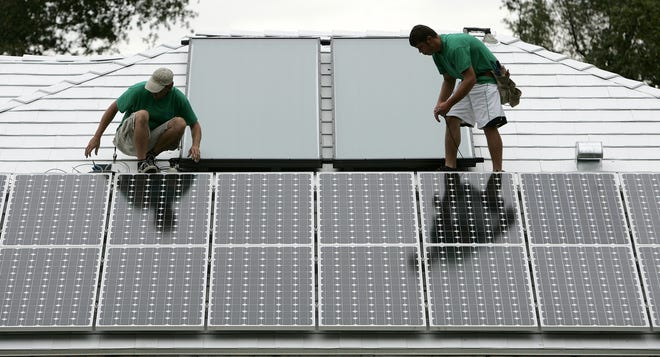 Workers install solar panels on a Gainesville home. A new co-operative program starting in Alachua County will give homeowners information on solar energy and discounts on adding solar energy to their homes. [Gainesville Sun file photo]