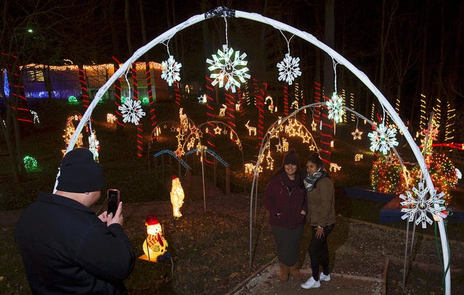 Victor Gonzalez (left) takes a photograph on Dec. 8 of Perla Gonzalez (center) and Maria Villegas among the Christmas lights at the 2018 Winter Wonderland Light Festival held at Light of the World Church. [Donnie Roberts/The Dispatch]