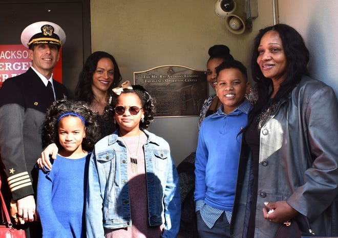 Naval Air Station Jacksonville (NAS Jax) Commanding Officer Capt. Michael Connor, left, gathers with Claribel Edmond, second from left, and family members in front of the plaque naming the Emergency Operations Center after her husband Ray Edmond, NAS Jax emergency management officer, who passed away in April.