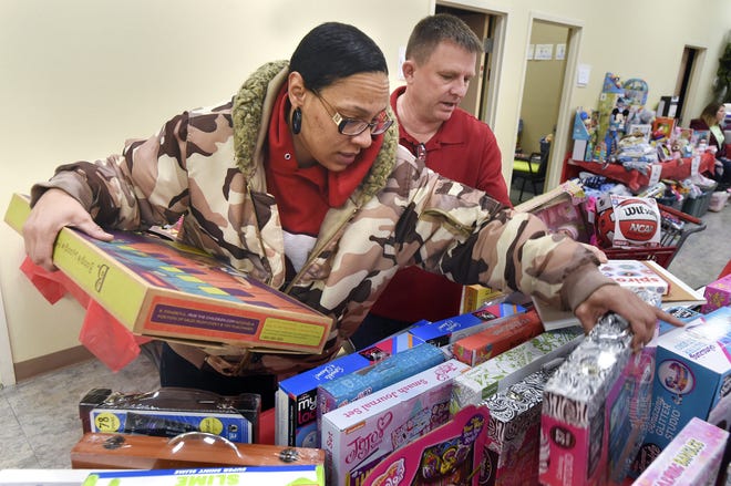 Kami Brown picks out some Christmas gifts for her children with the help of volunteer David Beale on Wednesday at the Salvation Army. About 500 children received gifts this year through Christmas Connections, a partnership between Catholic Charities, the Salvation Army and The Matrix. [DEVON RAVINE/DAILY NEWS]