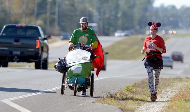Jamie McDonald, left, runs Tuesday on U.S. Highway 98 in Wynnhaven Beach with Niceville resident Brooke Thompson on the Northwest Florida leg of McDonald's adventure to run across the United States, running sometimes 40 miles per day, to raise money for children's hospitals. [NICK TOMECEK/DAILY NEWS]