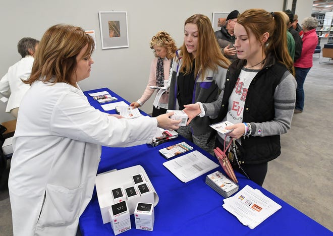 LECOM pharmacy professor Kim Burns, 47, at left, hands Narcan kits to sisters Susie Guisto, 21, center, and Madi Guisto, 19, at right, during a giveaway event at Blasco Memorial Library on Thursday. The state Department of Health provided free of charge about 120 kits, each of which contained two doses of Narcan, which can help reverse the effects of an opioid overdose. The Guistos, of Emporium, Cameron County, are both nursing students at Edinboro University of Pennsylvania. They wanted to have the kits in case of any opioid overdose emergency that they might encounter. [CHRISTOPHER MILLETTE/ERIE TIMES-NEWS]