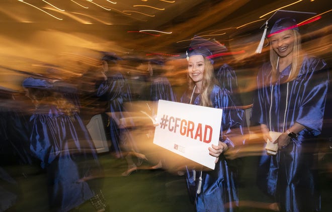 Leah Gilmer, left, carries the #CFGRAD sign while walking Friday. More than 1200 certificates and degrees and approximately 340 graduates walked in the College of Central Florida Commencement ceremony Friday afternoon at the First Baptist Church in Ocala. Natascha Kehri was the guest speaker talking about her struggle to move forward in life after witnessing the murder of her father while living in South America. [Doug Engle/Ocala Star-Banner]