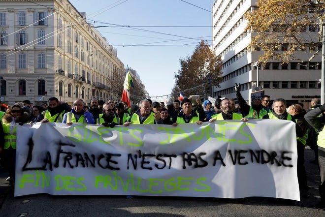 People wearing their yellow vests demonstrate with a banner reading "France is not for sell" Saturday in Marseille, southern France. Paris police deployed in large numbers Saturday for the fifth straight weekend of demonstrations by the "yellow vest" protesters, with authorities repeating calls for calm after protests on previous weekends turned violent.