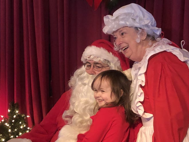 A young girl shares her Christmas wishes with Santa and Mrs. Claus on Saturday morning at Pancakes with Santa, an annual event at Magnolia Grill that benefits the Empty Stocking Fund. [JIM THOMPSON/DAILY NEWS]