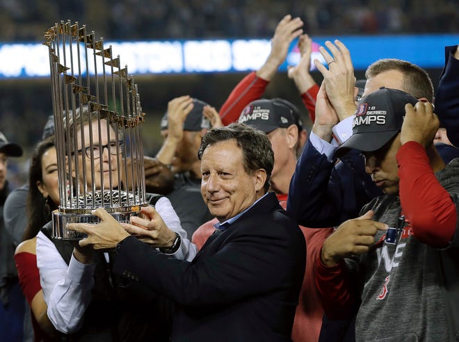 Owner John Henry, partially hidden at left, and chairman Tom Werner hold the championship trophy after Game 5 of the World Series.