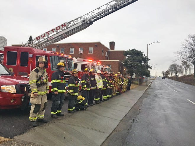 Firefighters from towns outside Worcester who are manning the Southbridge Street Fire Station for 24 hours during services for Firefighter Christopher Roy line the sidewalk as his funeral procession approaches.