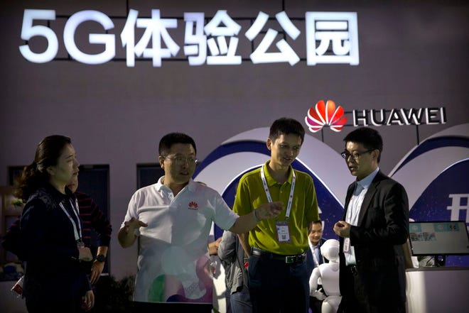 In this Sept. 26, 2018, file photo, visitors look at a display for 5G wireless technology from Chinese technology firm Huawei at the PT Expo in Beijing. While a Huawei executive faces possible U.S. charges over trade with Iran, the Chinese tech giant's ambition to be a leader in next-generation telecoms is colliding with security worries abroad.