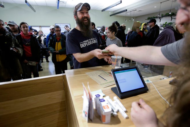 Gary Lola, center, purchases recreational marijuana at the Cultivate dispensary on the first day of legal sales, Tuesday, Nov. 20, 2018, in Leicester, Mass. Cultivate is one of the first two shops permitted to sell recreational marijuana in the eastern United States, more than two years after Massachusetts voters approved it in 2016. (AP Photo/Steven Senne)