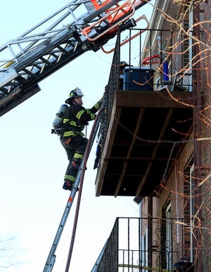 A Weymouth firefighter climbs onto the third floor balcony while fighting a fire at 46 Pond Street on Tuesday, Dec. 18, 2018. The fire started on the first floor and climbed up the pipe chase into the second and third floors of the apartment building. There were no injuries at the scene at the time. The call stayed at a single alarm. Braintree, Quincy, and Hingham fire covered the stations. It is thought that the fire was started by a plumber who was soldering a water pipe/ shower valve. [Wicked Local Staff Photo/ Robin Chan]