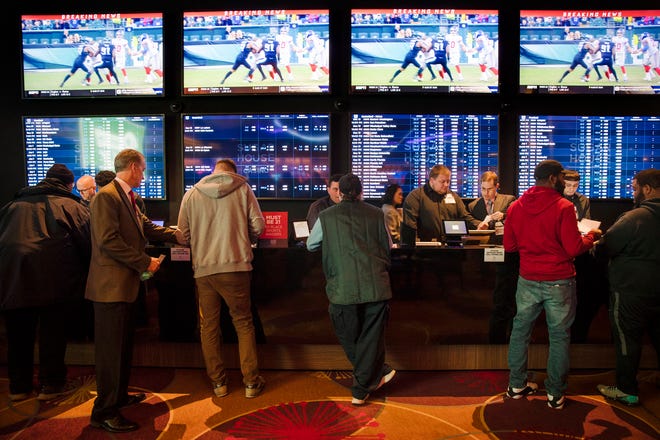 FILE - In this Thursday, Dec. 13, 2018, file photo, gamblers place bets in the temporary sports betting area at the SugarHouse Casino in Philadelphia. The federal government would regulate sports betting nationwide under a bill to be introduced Wednesday, Jan. 19,2018. The bill would have the U.S. Justice Department set minimum standards states must meet in order to offer sports betting, but denies the sports leagues the so-called â€œintegrity feesâ€ they have been seeking in new legislation, essentially a cut of sport betting revenue. (AP Photo/Matt Rourke, File)