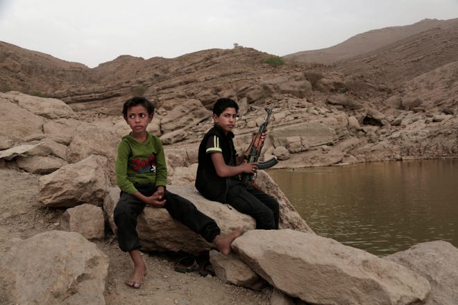 In this July 30, 2018, photo, a 17 year-old boy holds his weapon in High dam in Marib, Yemen. Experts say child soldiers are “the firewood” in the inferno of Yemen’s civil war, trained to fight, kill and die on the front lines. Though both sides in the war recruit children, the Houthi rebels rely on them the most. One Houthi military official said 18,00 children had been recruited over the past four years. (AP Photo/Nariman El-Mofty)