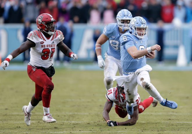 North Carolina quarterback Cade Fortin (6) runs the ball as North Carolina State's Jarius Morehead (31) and Stephen Griffin (21) chase during the first half of an NCAA college football game in Chapel Hill, N.C., Saturday, Nov. 24, 2018. (AP Photo/Gerry Broome)