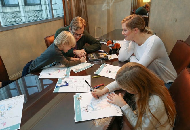 A family works on puzzles included in complimentary backpacks provided with other incentives by the Wyndham Grand Hotel in Chicago on Dec. 1. A growing number of hotels are offering incentives to guests willing to lock up their cell phones. [THE ASSOCIATED PRESS]