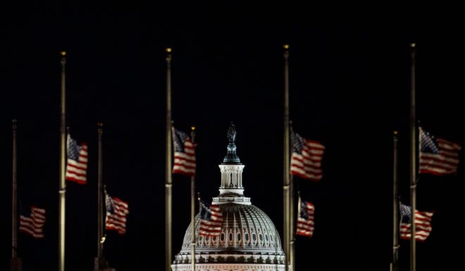 The U.S. Capitol Dome is seen beyond American Flags around the the base of the Washington Monument in Washington, early Saturday. The American Flags are at half-staff to honor of former President George H.W. Bush. Hundreds of thousands of federal workers faced a partial government shutdown early Saturday after Democrats refused to meet President Donald Trump's demands for $5 billion to start erecting a border wall with Mexico. Overall, more than 800,000 federal employees would see their jobs disrupted, including more than half who would be forced to continue working without pay.