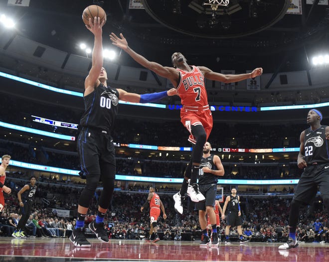 Chicago Bulls forward Justin Holiday (7) and Orlando Magic forward Aaron Gordon (00) reach for a rebound during their game Friday night in Chicago. [DAVID BANKS/THE ASSOCIATED PRESS]