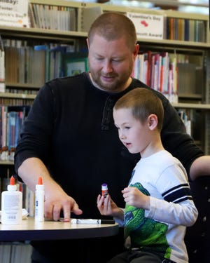Matt Summerhill helps his son, Corvin, 6, make Christmas crafts Friday, Dec. 21, 2018, during the Holiday Crafternoon at the Miller Branch Library. The library staff provided free crafting materials as well as milk and cookies. [JAMIE MITCHELL/TIMES RECORD]